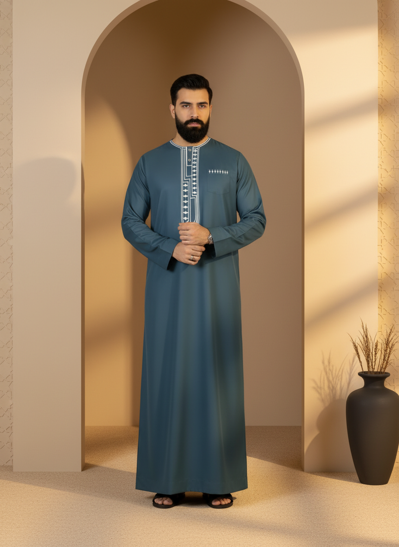 Male model wearing an elegant, modern MOONQADIR garment in a minimalist setting with arches and warm lighting.